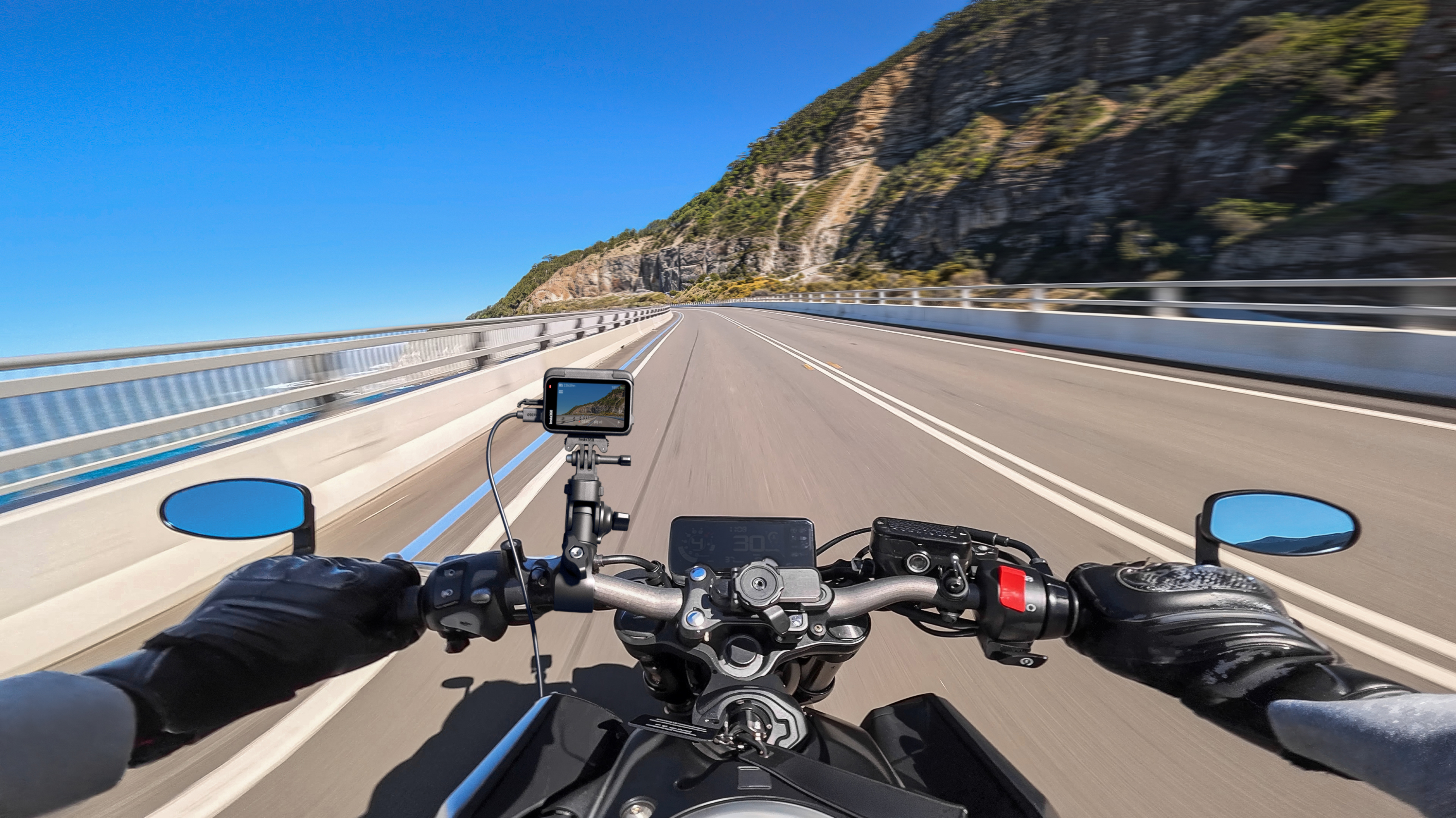 View of a mountain road from a motorcycle with Insta360 Ace Pro 2 mounted onto the handlebars.